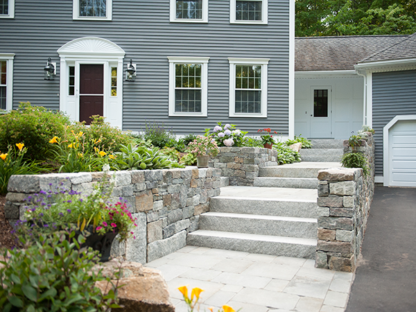 Stone wall and bluestone walkway in this Bedford NH landscape designed and installed by Stone Blossom
