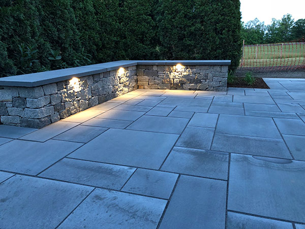 Stone patio and sitting wall with landscape lighting in Bedford NH