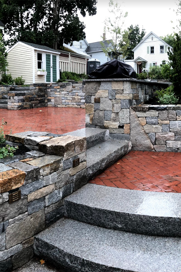 Landscaping project with stone walls and outdoor kitchen in Concord NH by Stone Blossom